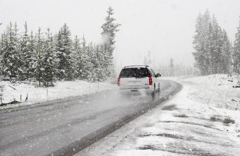 White SUV driving through snow on an icy surface